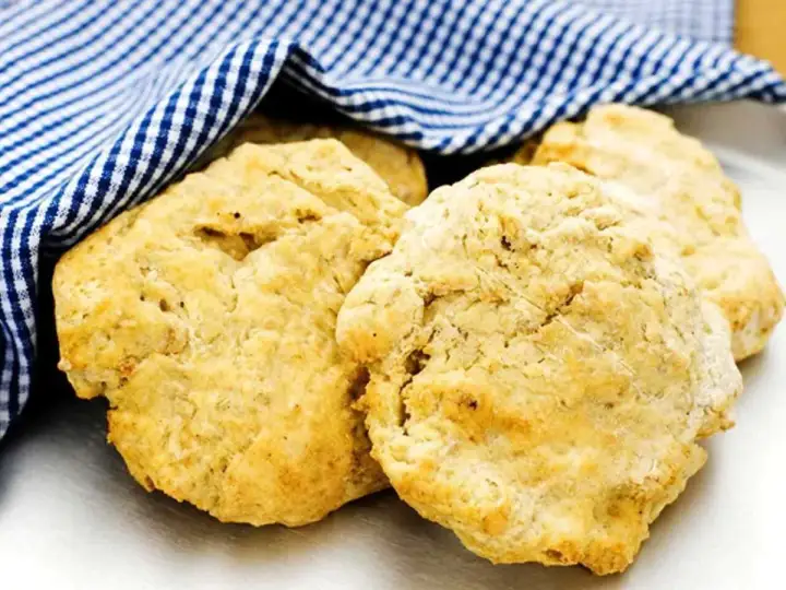 Nyttiga scones, gyllene och fluffiga, vilar under en blåvitrutig handduk. Perfekt för en hälsosam fika.